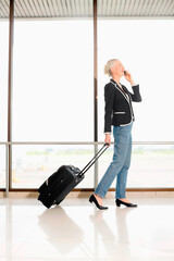 Businesswoman talking on the phone while pulling her luggage