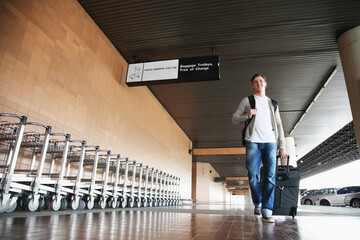 Obraz premium Man pulling his luggage pass luggage carts at the airport
