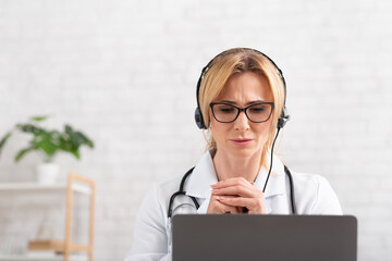 Complaints to doctor. Attractive adult woman with headphones focused listens to patient