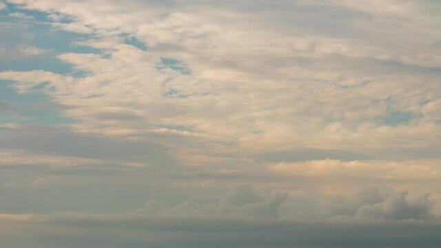 Fluffy white and grey clouds moving fast in time-lapse. Idyllic cloudy heaven background. Timelapse of beautiful clouds in sky in evening sunlight, perfect background for your title text or logo