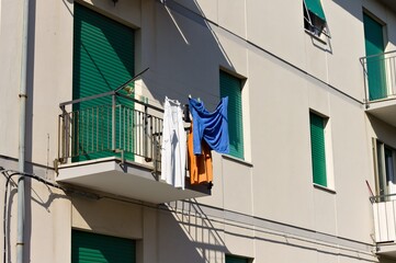 Clothes hanging on a wire out of the balcony of a house with green shutters (Pesaro, Italy, Europe)