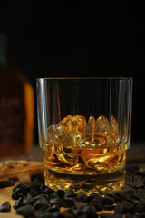 Glass of scotch whisky in ice with the bottle background.