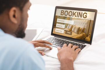 African american man browsing hotel booking website on laptop
