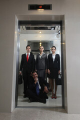 Business people standing while businessman sitting on the floor of elevator © ImageHit