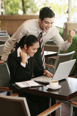 Business people cheering while using laptop