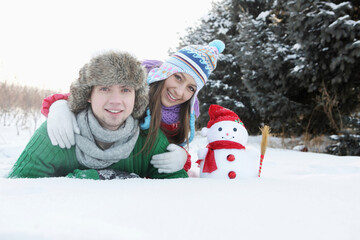 Man and woman posing with snowman