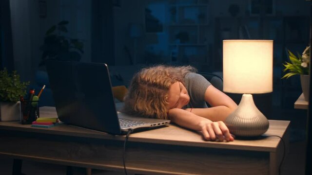 Young woman fell asleep at a desk working late at home with a laptop