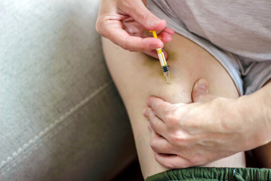 Photo of a female make insulin self injection in hip. Close-up shot of young women taking medication. Injecting her self. Healthy and medical concept.