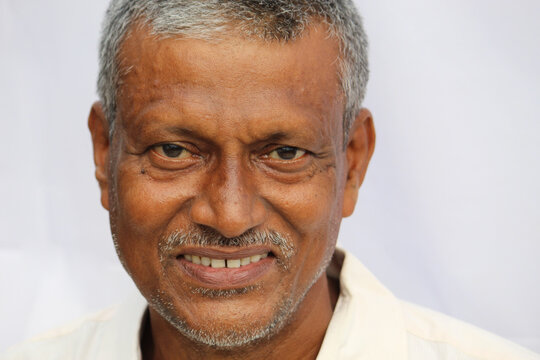 Smiling Indian senior man face portrait on white background.