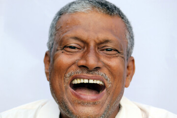 Naklejka premium Loud laughing open mouth of a Indian senior man on white background.