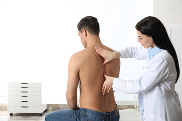 Professional orthopedist examining man in medical office