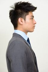 Profile view of young handsome Asian businessman in suit