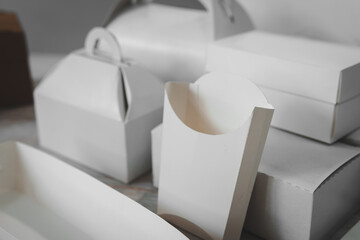Different types of white cardboard packaging. For fast food, folding, large and small. The concept of production and design of paper products. Place for text. Selective focus. copy space