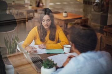 Positive students in casual wear working on common project during distance work with startup project on portable pc connected to 4g wireless