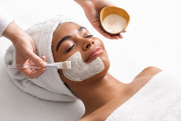 Top view of beauty therapist applying face mask