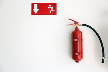 Obraz premium Fire extinguisher and emergency exit sign on white wall, space for text