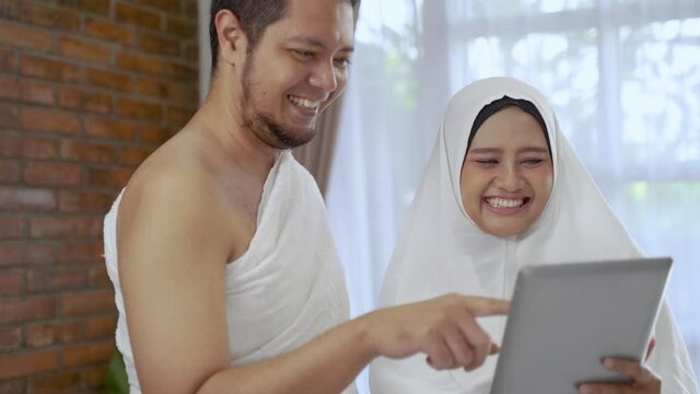 asian muslim couple hajj using tablet for video call with family