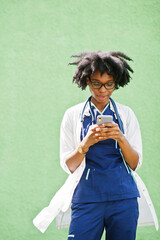 Portrait of African American female doctor with stethoscope wearing lab coat, speaking by mobile phone.