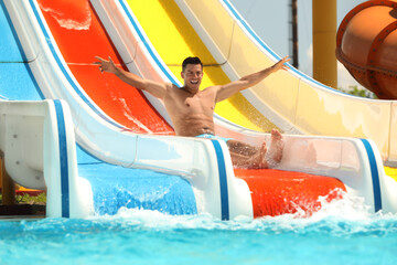 Man on slide at water park. Summer vacation