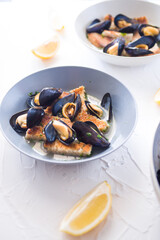 Steamed mussels bread slice and lemon on ceramic bowl, fresh fish mussels daily taken from sea cooked on a white background