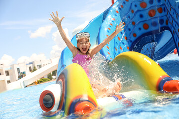 Little girl on slide at water park. Summer vacation