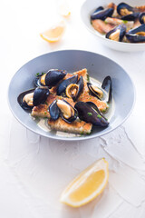 Steamed mussels bread slice and lemon on ceramic bowl, fresh fish mussels daily taken from sea cooked on a white background
