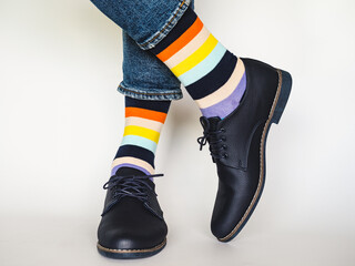 Men's legs, trendy shoes, blue jeans and variegated, long socks on a white, isolated background....