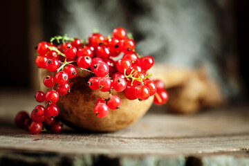 Fresh red currants in a Cup on a dark rustic wooden table. Background with space for copying. Selective focus.