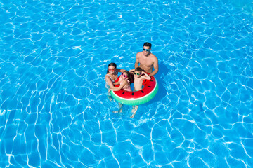 Happy family with inflatable ring in swimming pool. Summer vacation