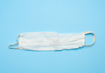 reusable mask of white cotton gauze on a blue background, homemade remedy for viral diseases