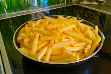 Yellow sliced potatoes in a frying pan.