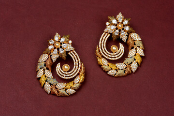 Glamorous antique Golden pair of earrings on red background. Luxury female jewelry, Indian traditional jewellery, kundan earring,Bridal Gold earrings wedding jewellery,Vintage earring