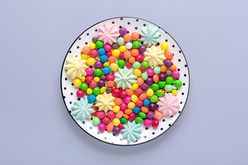 mix colorful sweets - white round plate with black peas, lollipop, meringue, chocolate, sprinkle on gray background Flat lay Top view Holiday card Happy birthday party, Thanksgiving day concept