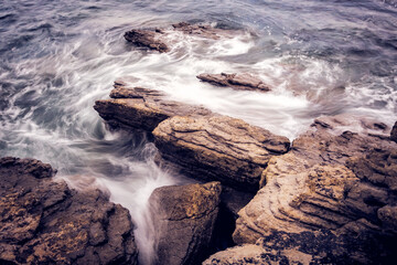 Coast with rocks and water. Silk water in a coast of Spain. Waves and rocks. Horizontal Composition