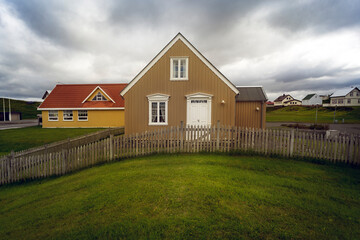 Fototapeta na wymiar Typical nice Icelandic house with dramatic clouds and green grass