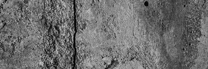 Texture of an old cracked concrete wall. Rough gray concrete surface. The gap between the reinforced concrete slabs. Wide panoramic background for design.