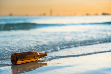 Obraz premium Brown glass bottle on Tawaen Beach in the dawn, the sun was rising, morning sunrise time on Koh Lan island.