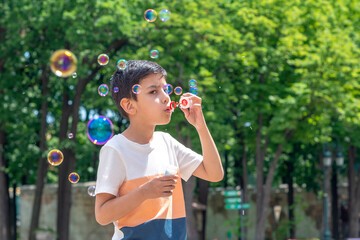 Shot of a young boy blowing bubbles in the park on vacation