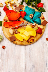 Cheese plate. Assorted multicolored hard Dutch cheeses. Blue and red pesto, aged gouda