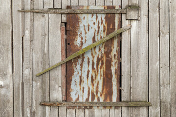 Old barn window with a lock made from rustic weathered wood.
