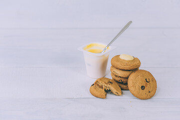 Oatmeal cookies with chocolate on a light background with yogurt.