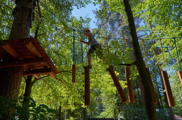 A boy with a helmet and insurance passes a high-altitude obstacle course.
