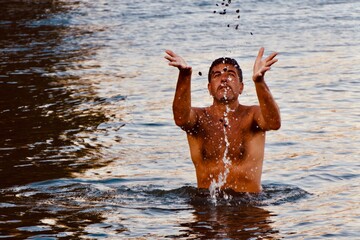 Shirtless Man Throwing Pebbles In Water