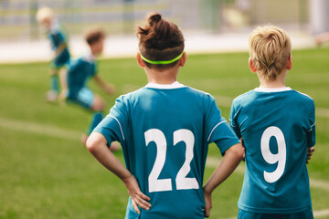 Boys watching football match outdoor. Back side of soccer jersey shirts with white numbers. Kids wearing sports clothes