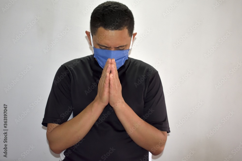 Sticker Closeup shot of a Latin male with mask praying on white background