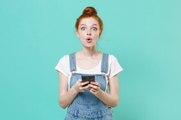 Shocked young readhead girl in casual denim clothes posing isolated on blue turquoise background...