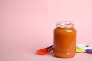 Jar with healthy baby food, spoon and toy on pink background, space for text