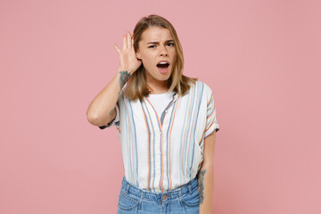 Shocked young blonde woman girl in casual striped shirt posing isolated on pastel pink background...