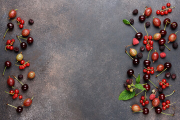 Ripe bright berries on brown background. Redcurrant, cherry, gooseberry, blackberry