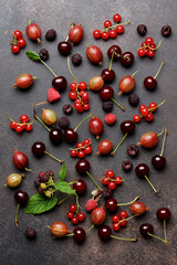 Ripe bright berries on brown background. Redcurrant, cherry, gooseberry, blackberry